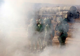 Russian soldiers wear chemical protection suits as they stand next to model of Russian Topol intercontinental ballistic missile during a training session at the Serpukhov's military missile forces research institute outside Moscow in 2010. (Natalia Kolesnikova/AFP/Getty Images)